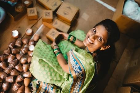 A lady sitting smiling and packing Dalit candles.